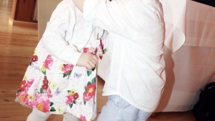 Zwei Kinder umarmen sich auf einer Feier in einem festlich dekorierten Raum mit Holzboden.