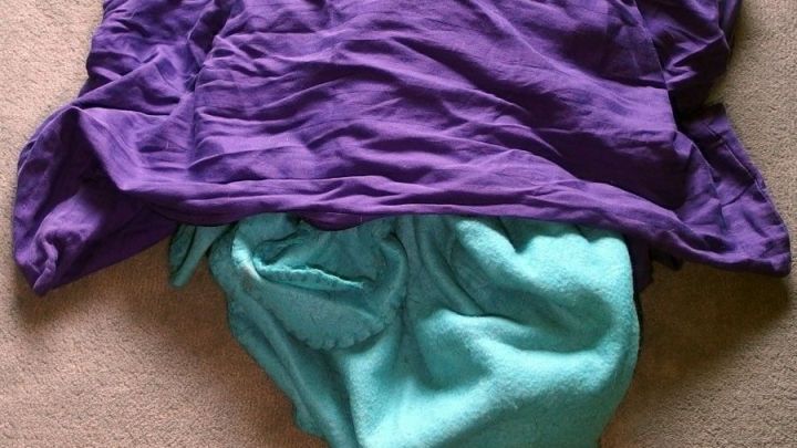 Ein lila und ein t&uuml;rkisfarbenes Kleidungsst&uuml;ck liegen &uuml;bereinander, bereit zum Waschen, um Tierhaare zu vermeiden.