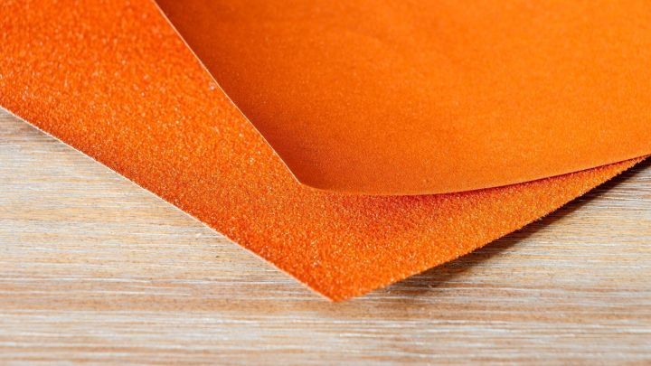 Ein orangefarbener Filz liegt auf einer Holzoberfl&auml;che und bietet eine weiche, farbenfrohe Grundlage f&uuml;r Reparaturprojekte.