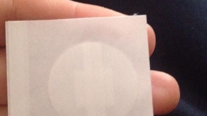 Ein Finger h&auml;lt ein wei&szlig;es, quadratisches Pflaster mit rundem Bereich. Der Hintergrund ist dunkelblau.