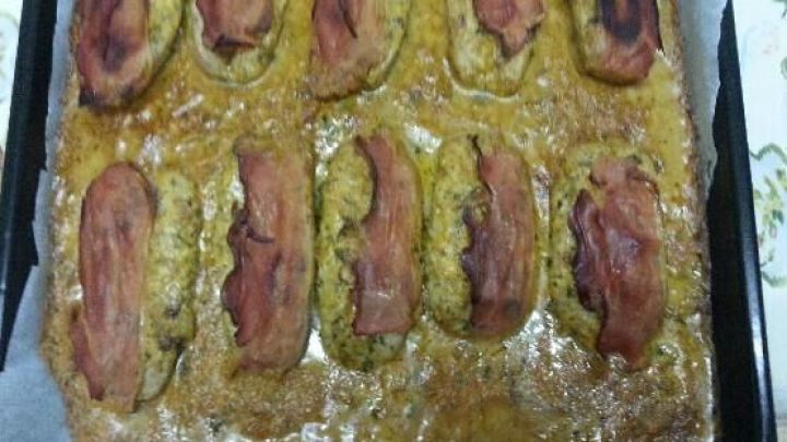 Bratw&uuml;rste, mit K&auml;se und Schinken &uuml;berbacken, liegen auf einem Backblech in einer K&uuml;che, bereit zum Servieren.