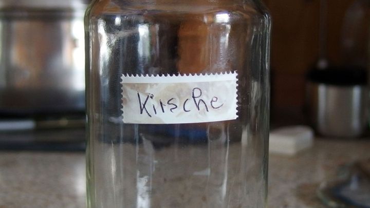 Ein leeres Marmeladenglas steht auf einer Tischoberfl&auml;che, etikettiert mit "Kirsche", bereit f&uuml;r die F&uuml;llung.