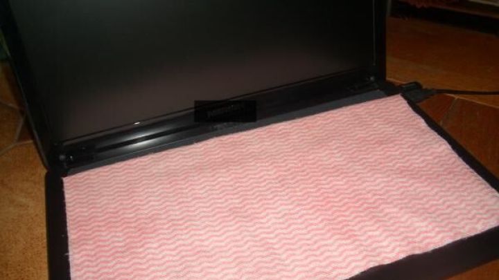 Ein einfacher Putzlappen liegt auf dem offenen Laptop-Monitor und sch&uuml;tzt ihn vor Staub und Schmutz in einem Wohnraum.