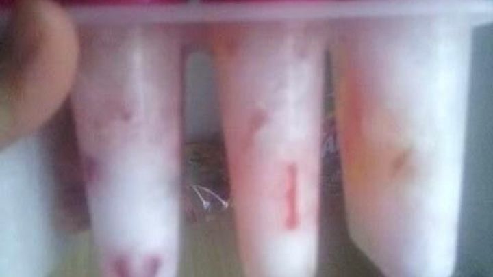 Eis am Stiel, gef&uuml;llt mit bunten Gummib&auml;rchen, wird in einem F&ouml;rmchen gehalten, bereit zum Genie&szlig;en an einem warmen Tag.