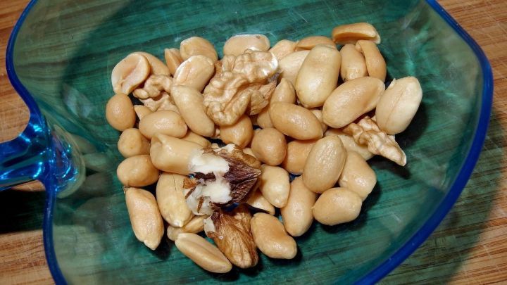 Eine Schale mit Erdn&uuml;ssen, in der sich einige gesch&auml;lte N&uuml;sse befinden, ideal zum Hamster f&uuml;ttern.