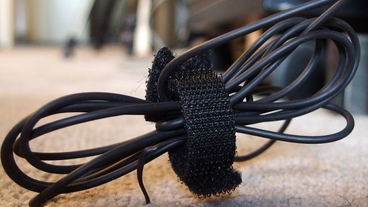 Ein Kabel ist ordentlich mit einem Klettband geb&uuml;ndelt, um Kabelsalat zu vermeiden, auf einem Teppich in einem Raum.