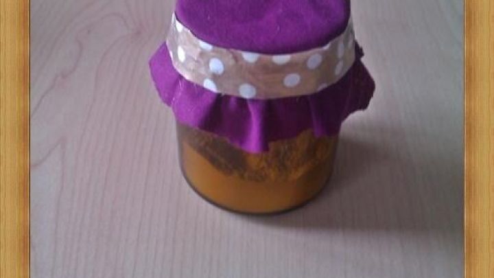 Ein Duftglas mit violettem Stoffdeckel steht auf einem Holztisch, verleiht dem Raum eine gem&uuml;tliche Atmosph&auml;re.