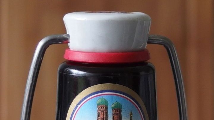 Eine schwarze Flasche mit einem B&uuml;gelverschluss steht vor einem hellen Hintergrund, bereit zum Abf&uuml;llen von Saft.