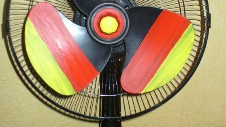 Ein Ventilator mit schwarz-rot-goldenen Fl&uuml;geln steht auf einem Tisch und bereitet sich darauf vor, die Luft zu bewegen.