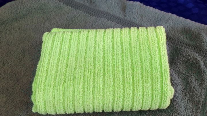 Ein weiches, gr&uuml;nes Handtuch liegt ordentlich gefaltet auf einem grauen Tuch, um Hautpflege bei unreiner Haut zu unterst&uuml;tzen.