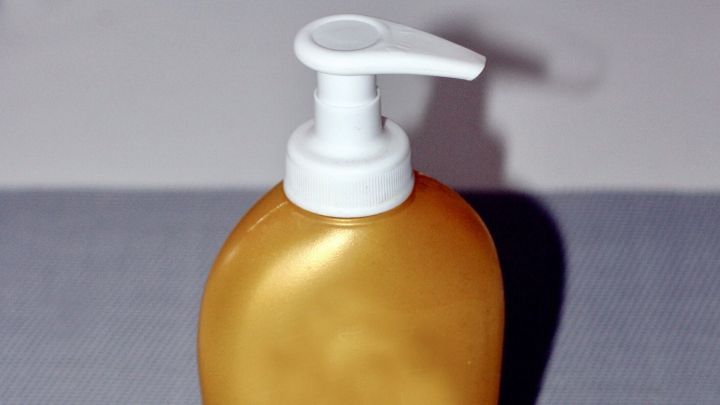 Ein goldfarbener Handcreme-Spender steht auf einem grauen Untergrund mit einem Sternmuster.