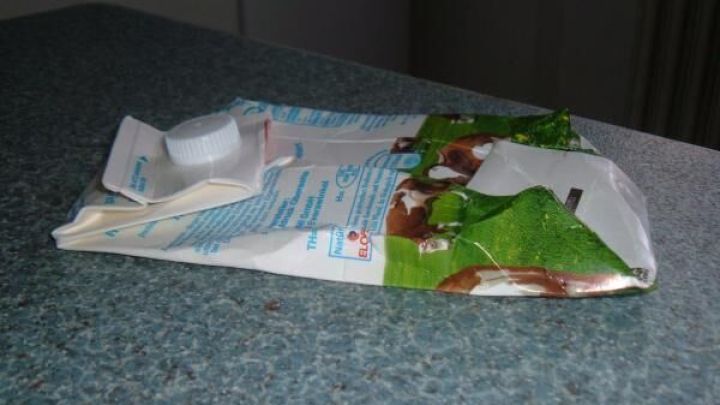 Ein zusammengefalteter Verpackungskarton liegt auf einer Arbeitsfl&auml;che. Er wird vorbereitet, um im gelben Sack Platz zu sparen.