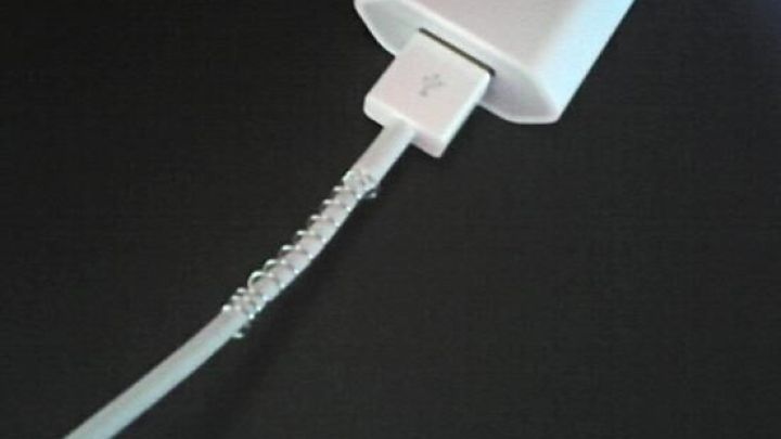 Ein Ladekabel mit Spiralfeder umwickelt, verhindert Kabelbruch beim Anschluss an ein wei&szlig;es Ladeger&auml;t auf schwarzem Untergrund.