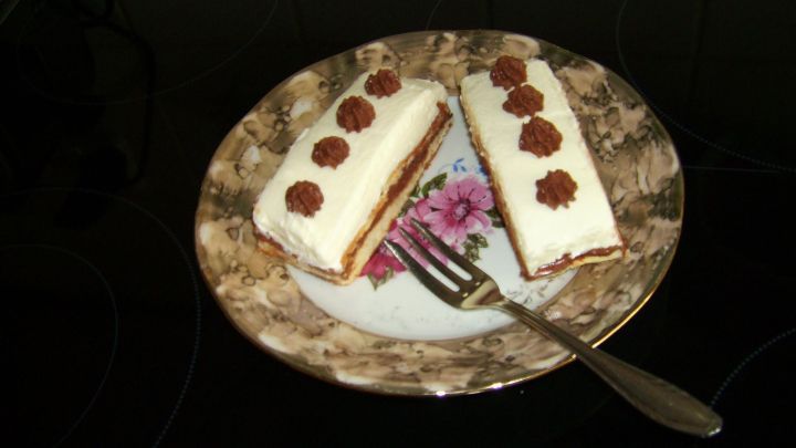 Zwei Mandelbiskuit-Schokoladenmousse-Schnitten liegen auf einem verzierten Teller mit einer Gabel daneben.