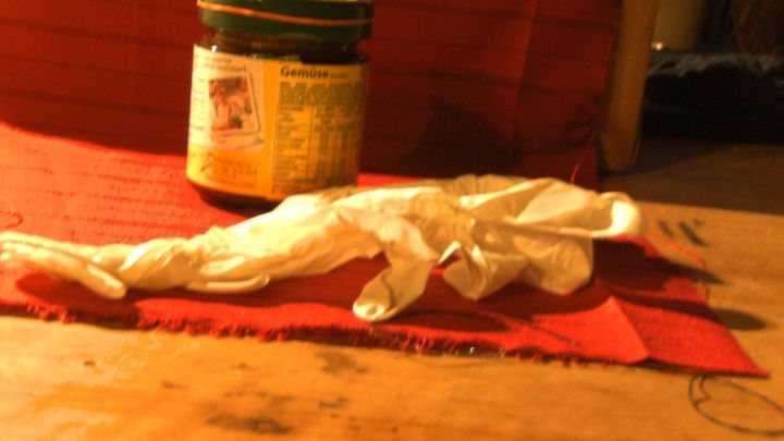 Ein Twist-off-Glas steht auf einem roten Stofftuch, daneben liegen wei&szlig;e Einweghandschuhe. Im Hintergrund ist ein unscharfer Raum. Der Text auf dem Glas lautet &bdquo;Gem&uuml;se&ldquo;.