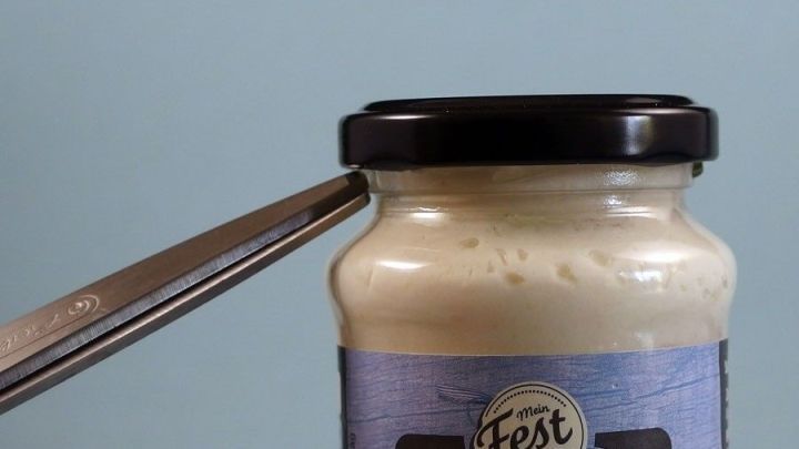 Ein Schraubglas mit einem schwarzen Deckel wird mit einer Zange ge&ouml;ffnet, um einen Inhalt freizugeben.