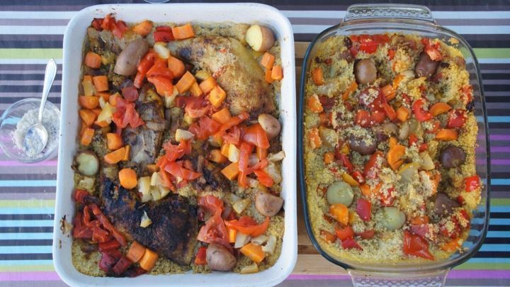 Couscous-Auflauf in zwei Backformen mit bunter Gem&uuml;se-Mischung auf gestreiftem Untergrund, daneben eine kleine Sch&uuml;ssel mit L&ouml;ffel.