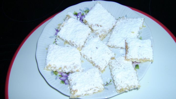 Zarte Apfelsaftpl&auml;tzchen liegen auf einem wei&szlig;en Teller, bestaubt mit Puderzucker, umgeben von dunklem Hintergrund.