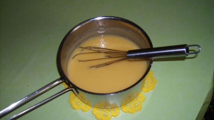 Ein Topf mit gelber Tortenf&uuml;llung wird mit einem Schneebesen auf einem gr&uuml;nen Tisch gemischt. Datum: 09/07/2014 14:32.