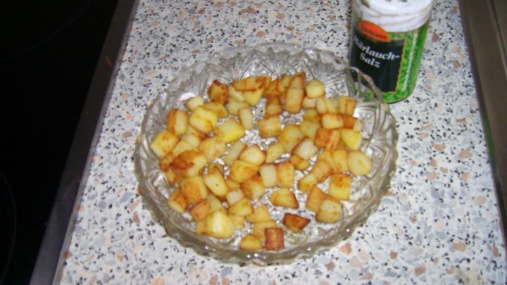 Gebratene, gew&uuml;rfelte Kartoffeln auf einem Glasteller; daneben steht eine Dose Knoblauch-Salz auf einer Arbeitsplatte. Datum: 10/07/2014 10:52.