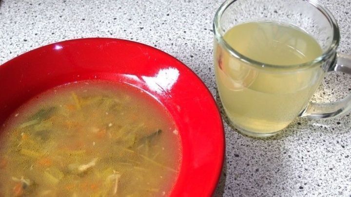 Eine Sch&uuml;ssel H&uuml;hnersuppe steht neben einer Tasse Lindenbl&uuml;tentee auf einem Attributtisch, bereit zur Linderung von Erk&auml;ltungsbeschwerden.