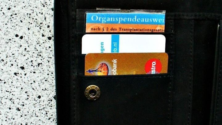 Eine schwarze Geldb&ouml;rse zeigt einen Organspendeausweis und diverse Karten. Daneben liegt ein Schl&uuml;sselanh&auml;nger auf hellem Tisch.