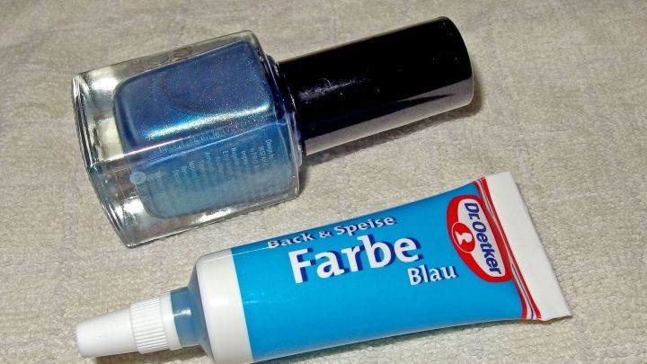 Ein blauer Nagellack und eine Tube mit blauer Farbe liegen zusammen auf einem hellen Untergrund, bereit zur Verwendung.