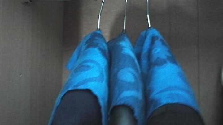 Drei Jacken h&auml;ngen in einem Schrank an einem Kleiderb&uuml;gel, verdeckt von blauen Stoffbez&uuml;gen zum Schutz vor Staub.