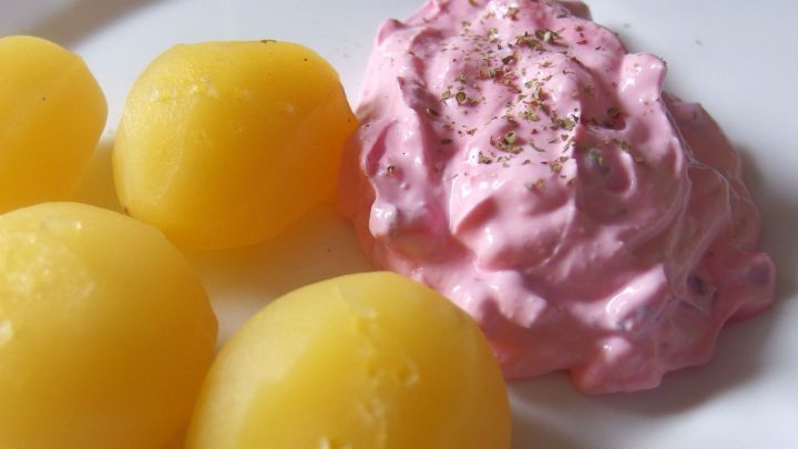 Pellkartoffeln sind auf einem Teller neben einer cremigen Rote-Bete-Quark-Mischung in leuchtendem Rosa angerichtet.