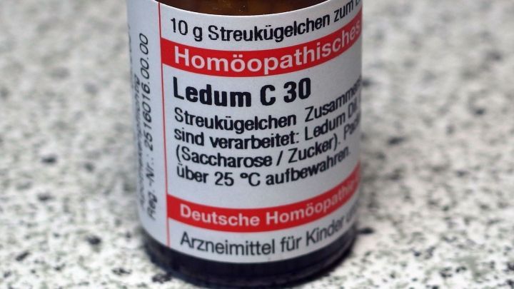 Ein kleines Fl&auml;schchen mit dem Etikett &bdquo;Hom&ouml;opathische&ldquo; sowie der Aufschrift &bdquo;Ledum C 30&ldquo; steht auf einer grauen, strukturierten Oberfl&auml;che.