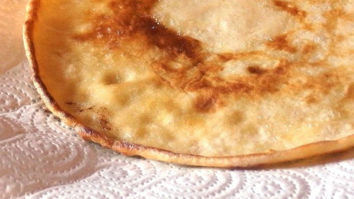 Ein goldbrauner Pfannkuchen liegt auf einem wei&szlig;en Papiertuch und zeigt seine leicht knusprige Textur.