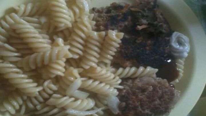 Drehte sich um Gem&uuml;se-Hack-B&auml;llchen, die auf einem Teller neben einem Nudelsalat angerichtet sind, alles auf einem Tisch.