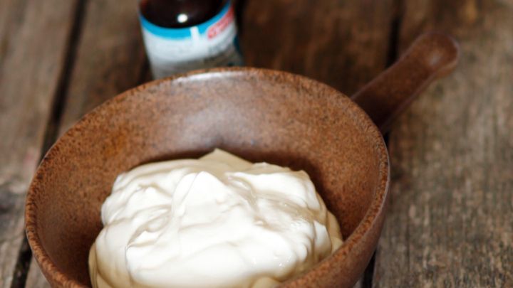 Eine braune Sch&uuml;ssel mit Quark steht auf einer rustikalen Holzfl&auml;che, daneben eine Flasche japanisches Minz&ouml;l.