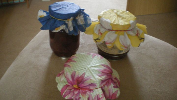 Bunte Marmeladengl&auml;ser mit dekorativen Stoffdeckeln stehen auf einem Tisch, bereit zum Verschenken und Versch&ouml;nern.