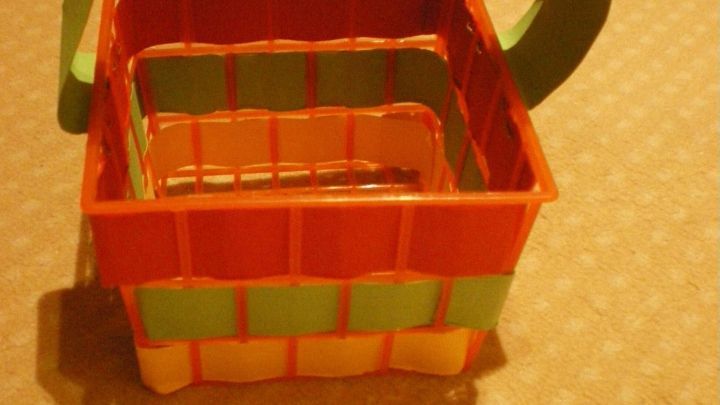 Ein buntes K&ouml;rbchen aus Papppapier steht auf einer hellen Unterlage, bereit f&uuml;r den Kindergeburtstag.