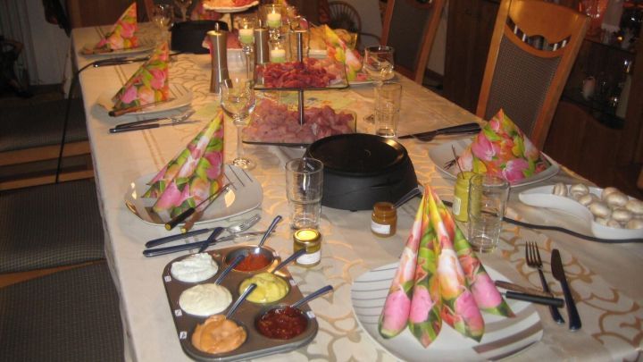 Ein gedeckter Tisch mit einer Muffinform, die f&uuml;r Grillso&szlig;en genutzt wird, umgeben von festlicher Dekoration und Kerzenlicht.