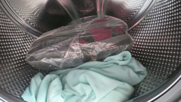 Eine gr&uuml;ne W&auml;sche liegt in einer Waschmaschine, w&auml;hrend ein einzelnes W&auml;schest&uuml;ck in Folie eingeschlagen daneben liegt.