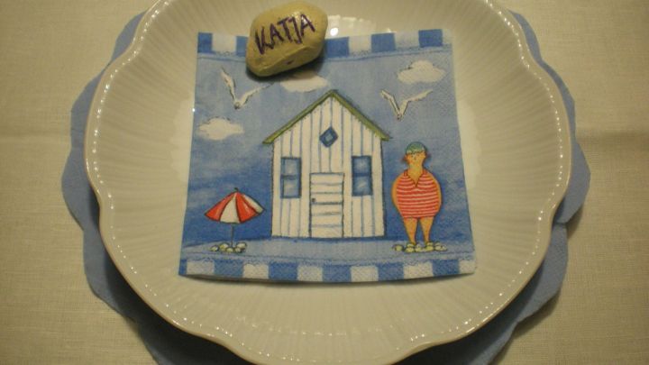 Ein maritimes Geburtstagsplatzset zeigt eine bunte Strandhaus-Szene mit einem geschmackvollen Teller und einer Muschel.