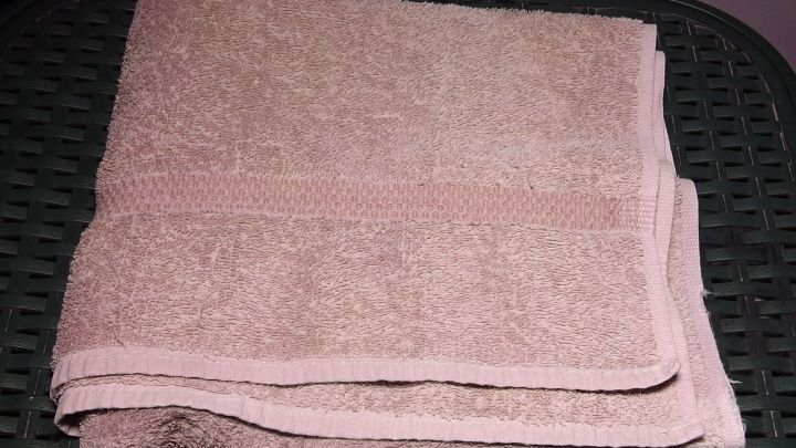 Ein gefaltetes, verwaschenes Handtuch liegt auf einem schwarzen Korb, bereit zur weiteren Verwendung in einem Badezimmer.