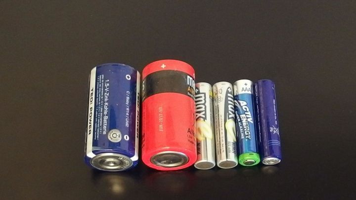 Verschiedene Batterien liegen nebeneinander auf einer dunklen Oberfl&auml;che, bereit zum Aufladen, um ihre Energie zu nutzen.