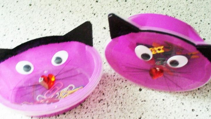 Zwei kreative Katzendosen im Gesicht-Design liegen auf einer Tischoberfl&auml;che und dienen als Aufbewahrung.