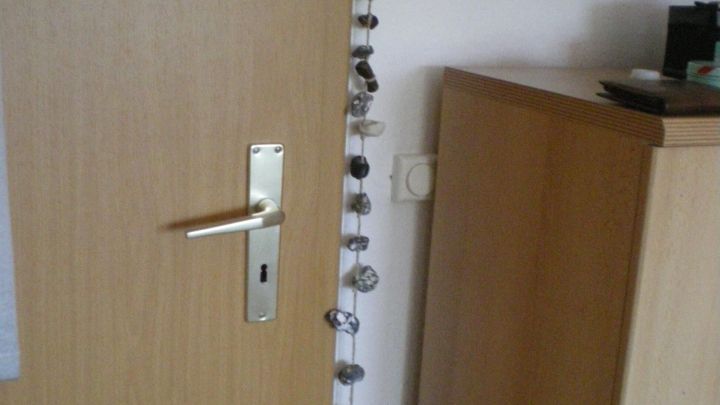 Eine T&uuml;r ist mit H&uuml;hnerg&ouml;ttern dekoriert, die von oben nach unten h&auml;ngen und den Eingang versch&ouml;nern.