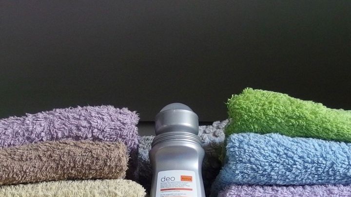 Auf einem Regal sind farbige Handt&uuml;cher angeordnet, w&auml;hrend ein Deo als Schrankerfrischer in der Mitte platziert ist.