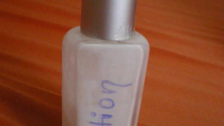 Eine durchsichtige Bodylotion in einem Seifenspender steht auf einer orangefarbenen Oberfl&auml;che.