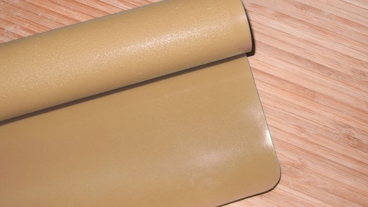 Eine Backfolie liegt gerollt auf einer Holzoberfl&auml;che, bereit zum Einsatz anstelle von Backpapier beim Backen.