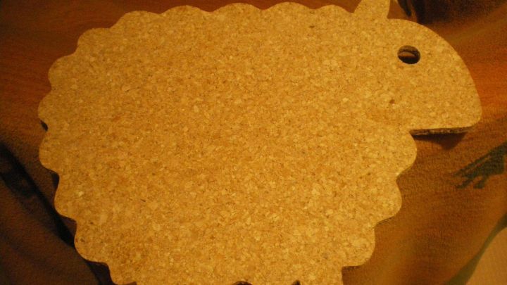 Ein Kork-Blumentopf-Untersetzer in Form eines Schafes liegt auf einem Tisch, um Pflanzen ansprechend zu st&uuml;tzen.