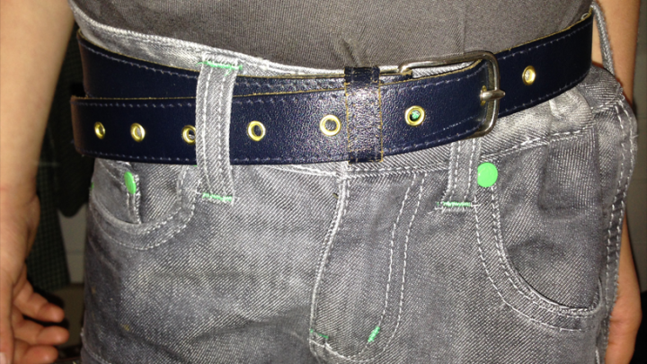 Ein blauer G&uuml;rtel h&auml;lt die Hose eines Tr&auml;gers an, w&auml;hrend er in einem ungezwungenen Umfeld steht.