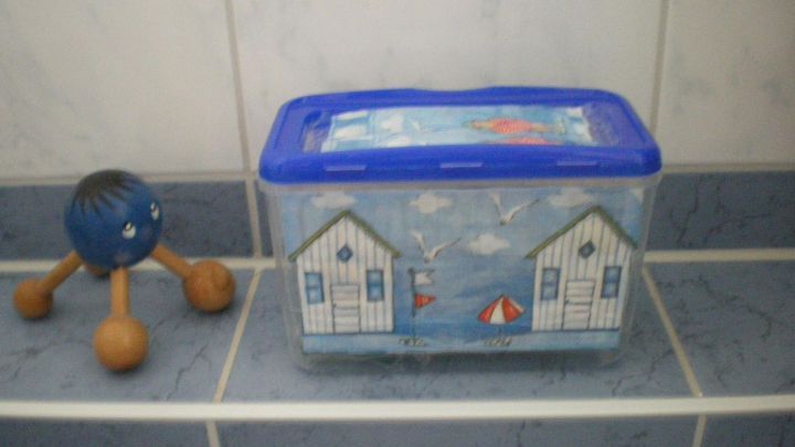 Eine dekorative Waschmitteldose steht auf einem Fliesenboden neben einem Holzspielzeug und f&uuml;gt dem Badezimmer Charme hinzu.