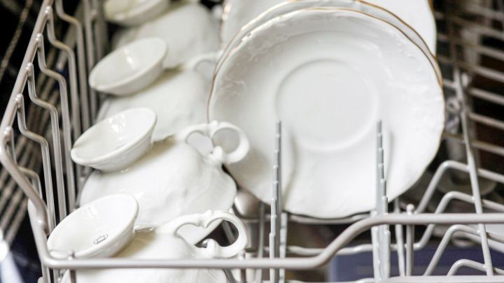 Ein Geschirrsp&uuml;ler enth&auml;lt wei&szlig;e Tassen und Teller, die bereit sind, gereinigt zu werden.