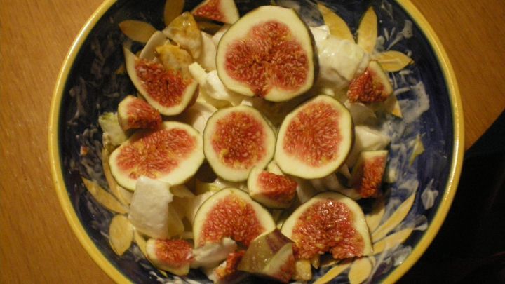 In einer bunten Sch&uuml;ssel liegen frisch aufgeschnittene Feigen, umgeben von einem Chicoreesalat, alles ansprechend angerichtet.